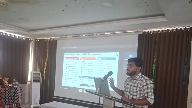 A man in a checked shirt speaks at a lectern beside a projected slide titled Technologies Used in Web Development.