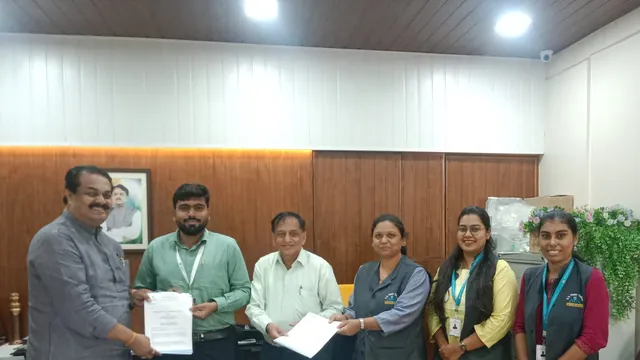 Six people pose in an office while two pairs each hold a printed document between them.
